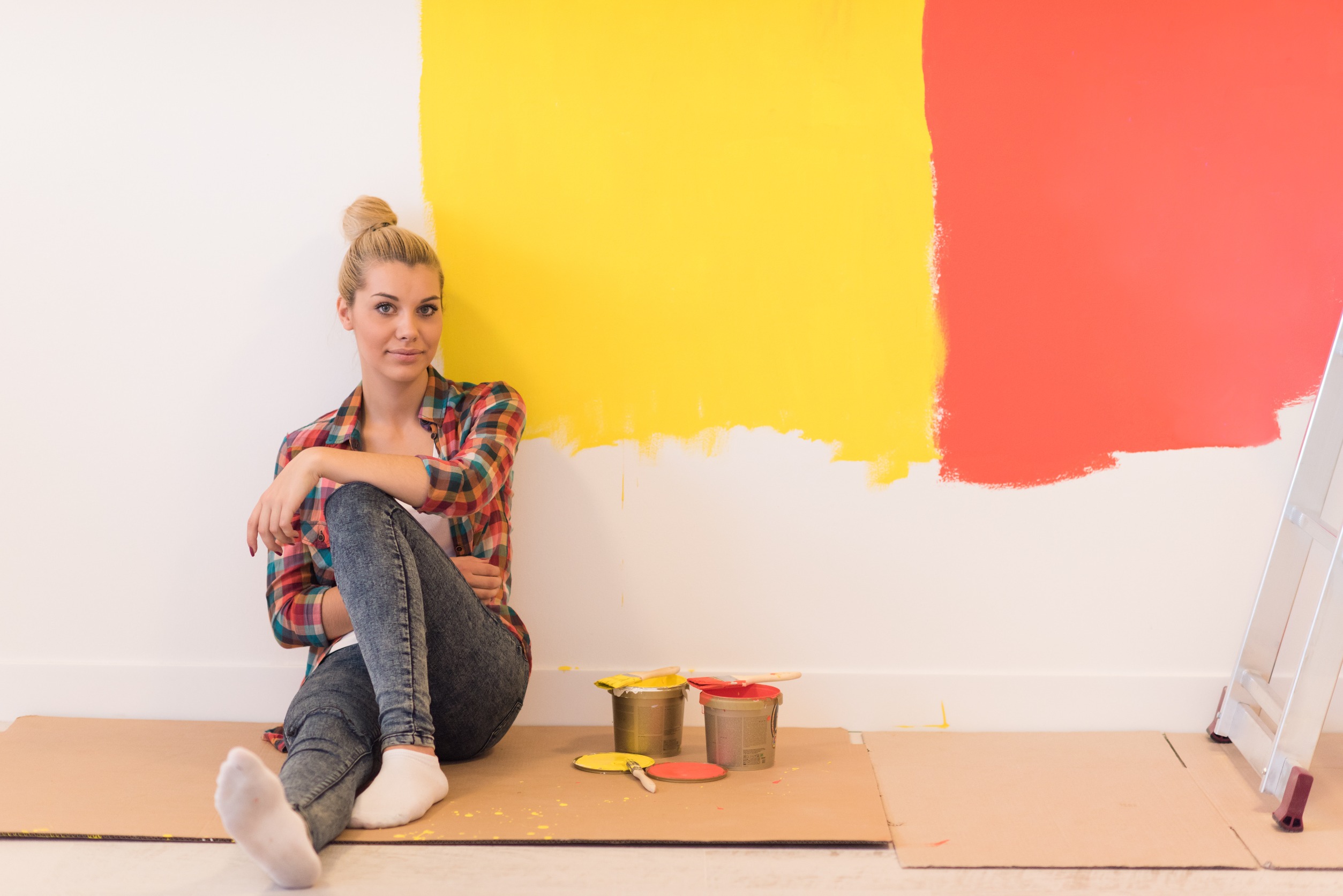 chica sentada contra la pared pintada de amarillo y rojo